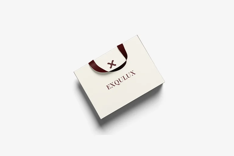 Exqulux paper bag mockup — a cream shopping bag with a wine-red ribbon handle, an "X" icon on the fold, and the Exqulux wordmark across the face
